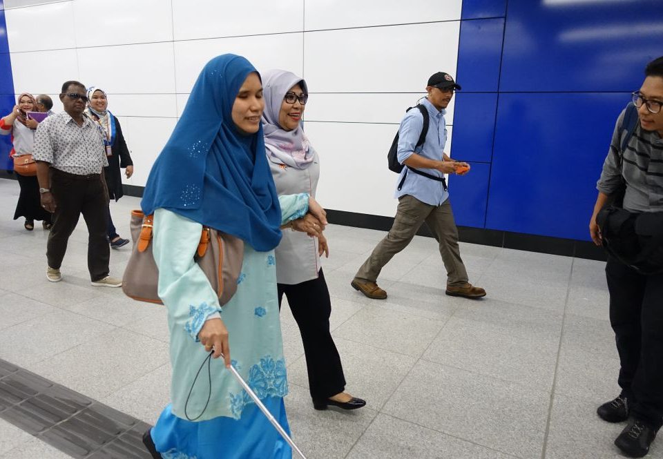 MEMIMPIN JALAN: Menteri Pembangunan Wanita, Keluarga dan Masyarakat Dato� Sri Rohani Abdul Karim (tengah) membantu seorang wanita buta berjalan di atas jubin sentuhan menuju ke aras platform di dalam Stesen Tun Razak Exchange.
