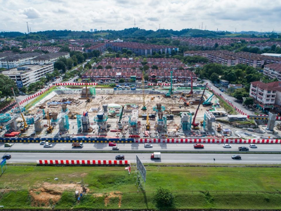 Pandangan udara pelancar segmen pratuang berbentuk T dan pembinaan cerucuk gerek dan tukup cerucuk untuk kemudahan tempat letak kereta bertingkat berhampiran tapak Stesen MRT Taman Equine.