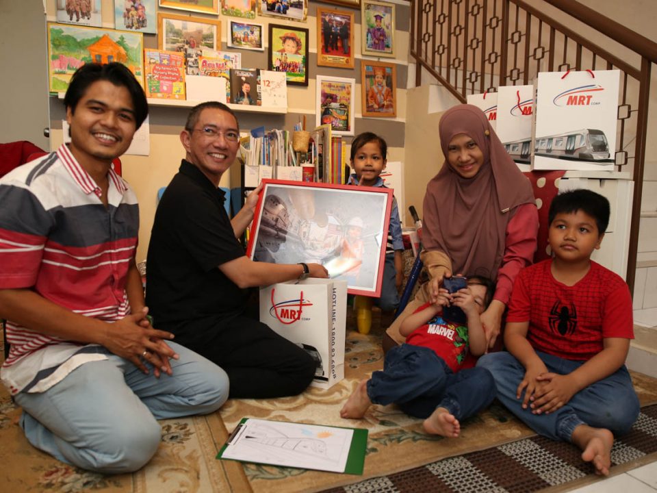 PENGHARGAAN: Pengarah Komunikasi Strategik dan Hal Ehwal Pihak Berkepentingan Malaysia Rapid Transit Corporation Sdn Bhd Dato’ Najmuddin Abdullah (berbaju hitam) menyampaikan hadiah tanda penghargaan kepada Ahmad Wazif (tengah) di atas sokongan dan minatnya terhadap MRT. Turut kelihatan adalah ibu bapa dan abang-abang Wazif.